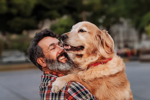 man holding his dog and smiling